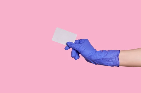 Kéz a kézben latex kesztyű birtokol egy névjegykártya, hitelkártya vagy üres papír elszigetelt — Stock Fotó