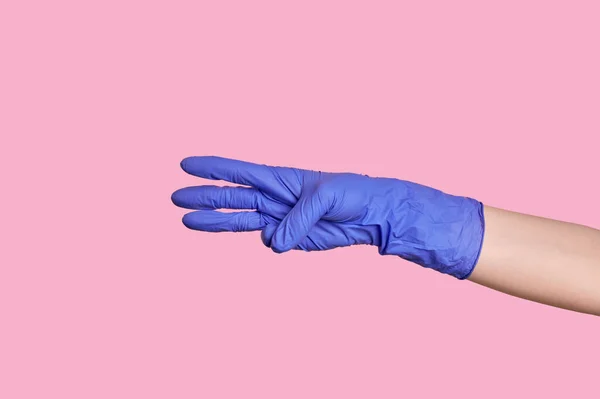 Číslo tři. Ruka v lékařské rukavici počítá na prstech. růžové pozadí. — Stock fotografie