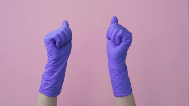 Dos brazos. Pulgar hacia arriba en guantes quirúrgicos, médicos, gesto. Fondo rosa . — Vídeo de stock