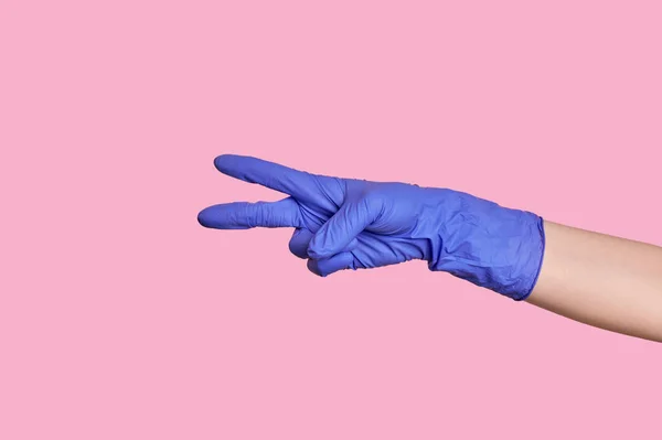 El número dos. La mano en un guante médico cuenta con los dedos. fondo rosa . — Foto de Stock