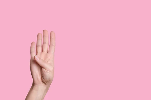 A négyes számú. A női kéz számít az ujjakon. rózsaszín háttér. — Stock Fotó