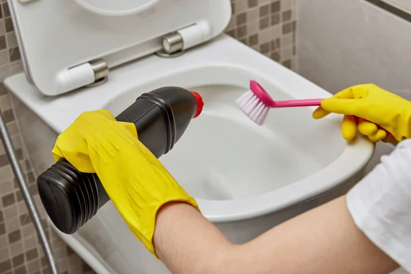 Reiniging van een wit toilet met huishoudelijke chemicaliën en een roze borsteltje.. — Stockfoto