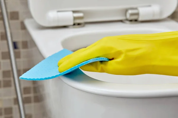 Close-up veeg de rand van het toilet af met een schoonmaakservet. Dagelijkse routine. — Stockfoto