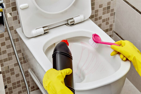Cleaning the toilet with household chemicals and a brush.