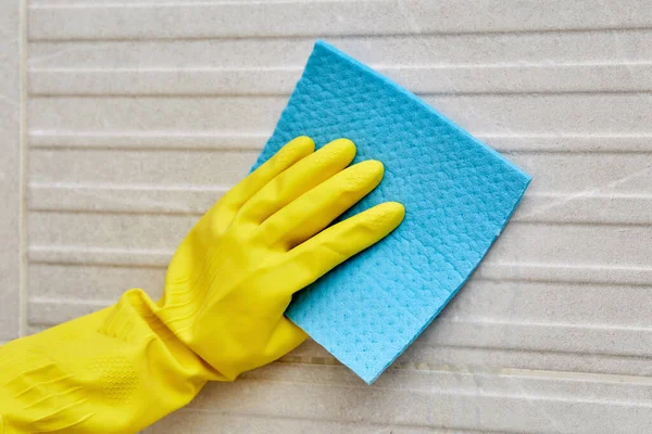 Close-up van een vrouwelijke hand in een beschermende handschoen met een schoonmaakservet. — Stockfoto