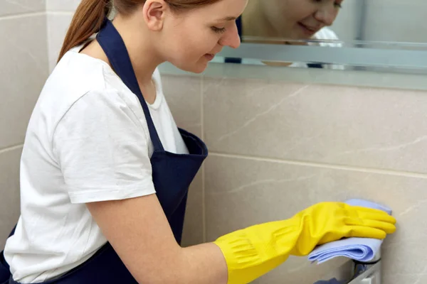 Lava un grifo de plata en el baño. Limpieza de la casa en guantes de látex amarillo . — Foto de Stock