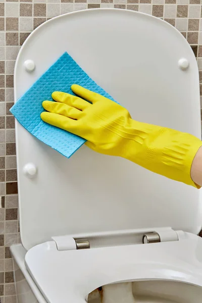 Close-up was het toiletdeksel in beschermende gele reinigingshandschoenen. Dagelijkse routine — Stockfoto