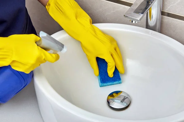 Meisje wast wastafel in badkamer met spons voor het wassen en huishoudelijke chemicaliën. — Stockfoto