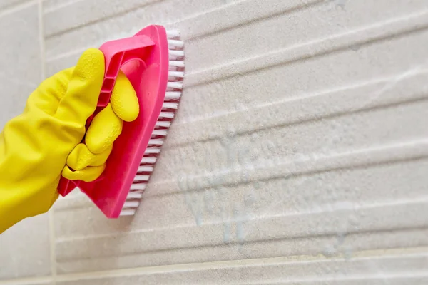 Hand in een gele rubberen beschermhandschoen met een borstel. Reiniging van de badkamer. — Stockfoto