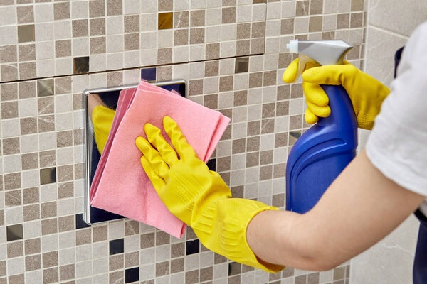Clean toilet water button. In the hands of a spray and rag for cleaning.