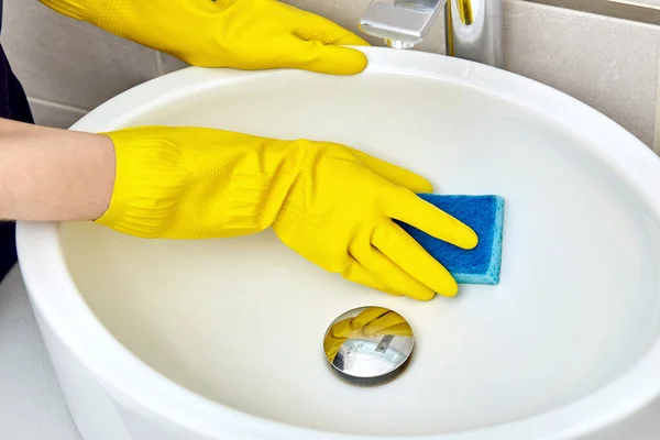 A professional cleaning company works. cleaning the bathroom. Wash the sink.