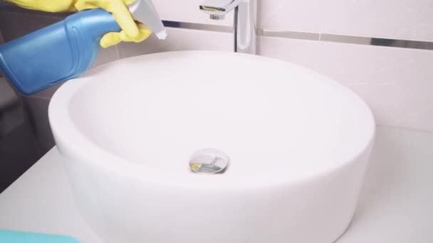 Una chica de servicio de limpieza pone detergente en el fregadero blanco y lo limpia con una servilleta . — Vídeos de Stock