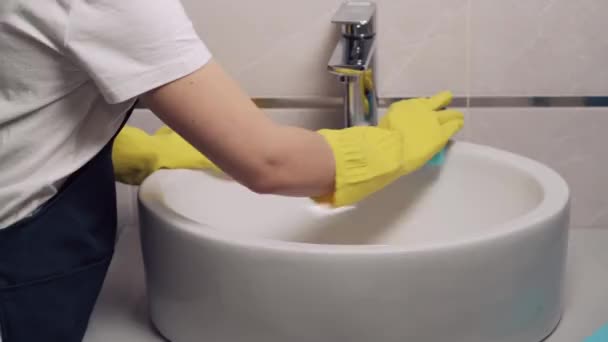 Ein junges Mädchen vom Reinigungsdienst wäscht ein Waschbecken im Badezimmer. Nahaufnahme. — Stockvideo
