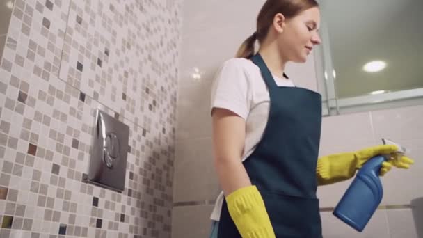 Ein junges Mädchen vom Reinigungsdienst wäscht ein Waschbecken im Badezimmer. Nahaufnahme. — Stockvideo