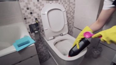 Kız tuvalete temizleyici koyuyor. Temizlik için lastik sarı eldivenler..