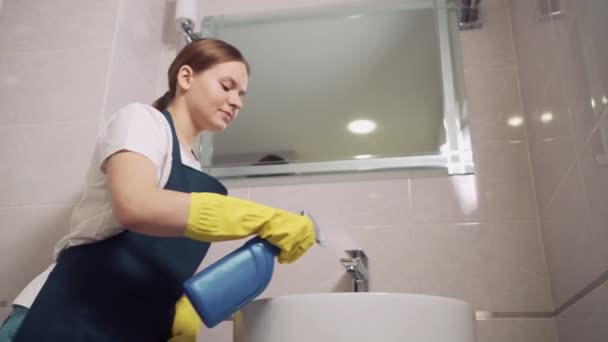 Krásná brunetka dívka myje kohoutek v koupelně. Nošení gumových rukavic. — Stock video