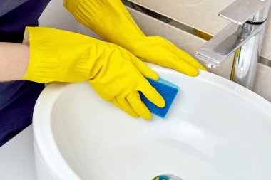 Kız banyo lavabolarını yıkamak için süngerle yıkıyor ve ev kimyasallarıyla yıkıyor..