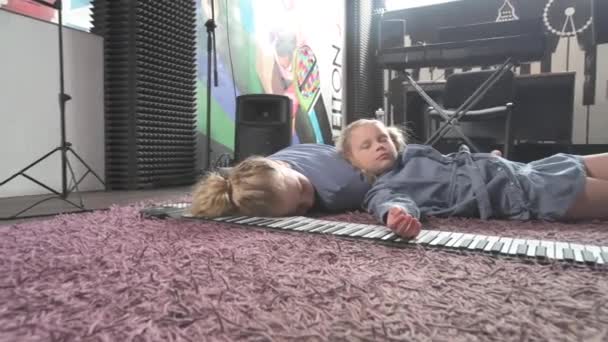 귀여운 금발의 두 자매가 악기를 연주하다가 지쳐 있었다. — 비디오