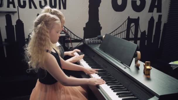 Две милые блондинки с яркими глазами вместе играют на пианино. . — стоковое видео