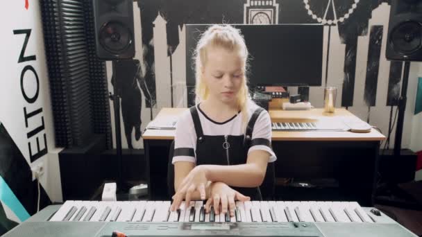 Retrato de una joven rubia tocando un sintetizador . — Vídeos de Stock