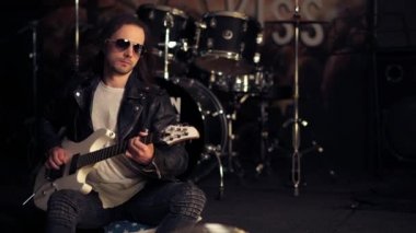 Elektro gitar çalan bir adam. Güneş gözlüklü acımasız adam..
