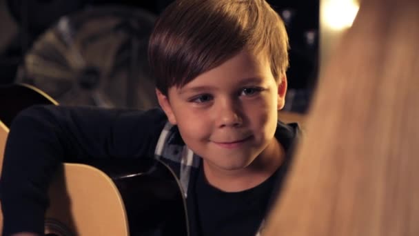 Cara de lindo niño sonriente que toca la guitarra y mira al maestro con amor . — Vídeos de Stock