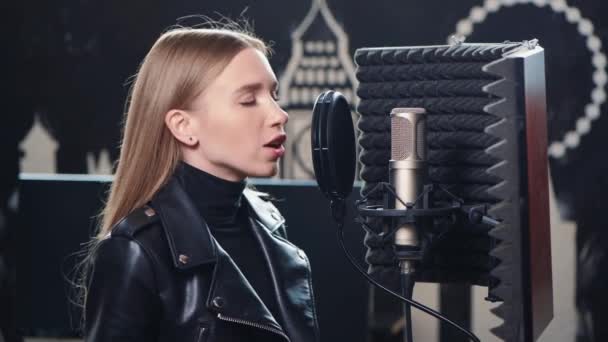 Close-up van mooi blond meisje is het opnemen van een lied in een opname studio. — Stockvideo
