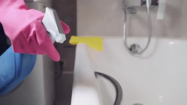 Primer plano de una niña aplicando un agente limpiador de un spray al borde de la bañera . — Vídeo de stock