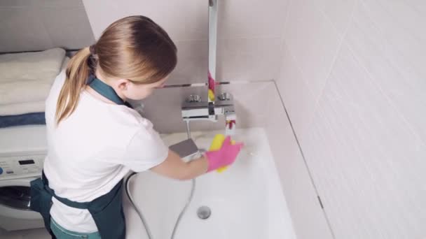Υπέροχη καθαρίστρια πλένει ένα μπάνιο. Χύνει νερό από μια κεφαλή ντους. — Αρχείο Βίντεο
