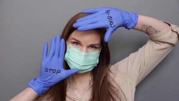 Kobieta w masce ochronnej i rękawiczkach pokazuje "stop COVID-19 — Wideo stockowe