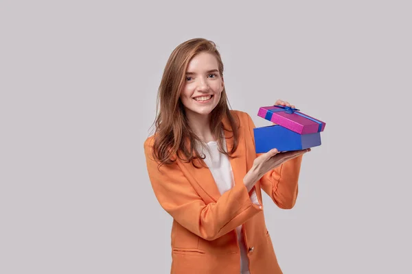 Счастливая симпатичная девушка смотрит в камеру с подарочной коробкой в руках . — стоковое фото