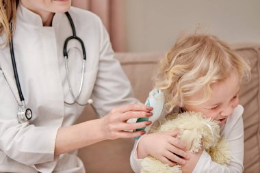 Güzel bebek başını yana çevirir, tatlı tatlı gülümser. Otoskop işitme testi.