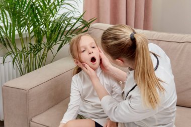 Çocuk hasta ve doktora boğazını gösteriyor..