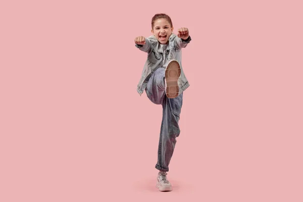 Полноразмерная девушка в модной джинсовой одежде и кроссовках. Розовый фон . — стоковое фото