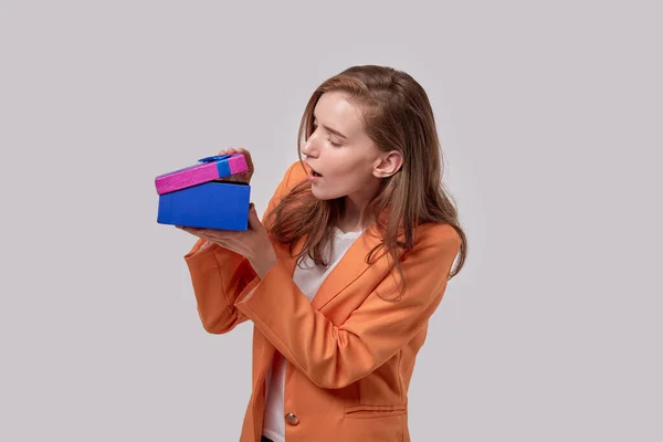 Una joven con una cara sorprendida abrió la caja de regalo. Regalos para las vacaciones . — Foto de Stock