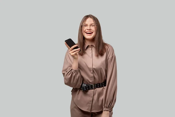 La morena en gafas sostiene el teléfono en sus manos y sonríe . — Foto de Stock