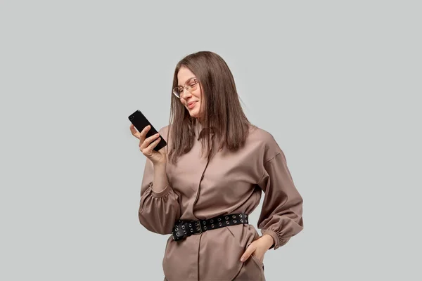 Elegante, hermosa mujer de negocios mirando a un teléfono inteligente y sonriendo . — Foto de Stock