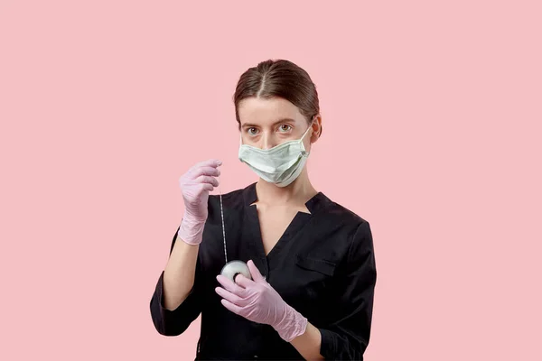 Het meisje met het masker ontspant en kijkt naar de camera. Roze achtergrond. — Stockfoto