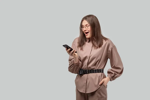 Una chica feliz está mirando su teléfono inteligente y es feliz . — Foto de Stock