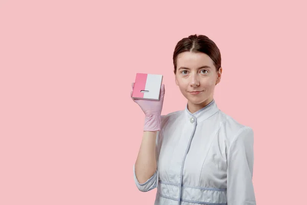 Молодая женщина держит маленькую коробочку с брекетами. Руки в медицинских перчатках . — стоковое фото