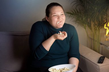 Televizyon izleyen patlamış mısır var. Güzel gülen kız. Vücut pozitif.