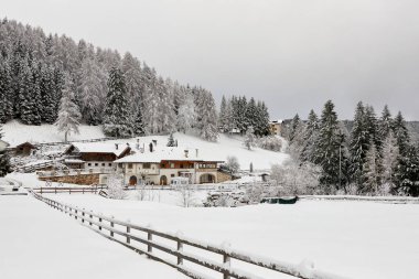 Karla kaplı evlerin manzarası. Ön tarafta ahşap bir çit var..