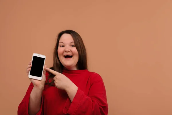 Una chica sonriente señala su mano a la pantalla en blanco de su teléfono . — Foto de Stock