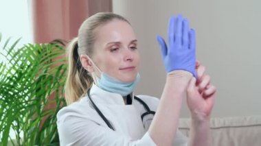 Kadın doktor, hasta bir çocuğu muayene etmek için tıbbi eldiven ve maske takıyor..