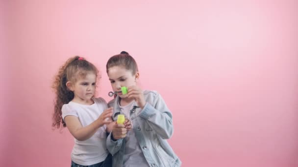 Dos hermosas hermanas alegres, felices y encantadoras soplan burbujas . — Vídeos de Stock