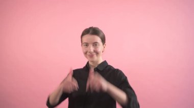 Başparmak gösteren bir kadın gülümseyen ve kameraya bakan..