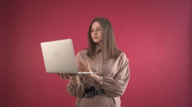 Genç iş kadını elinde dizüstü bilgisayarla çalışıyor. Gözlüklü kadın