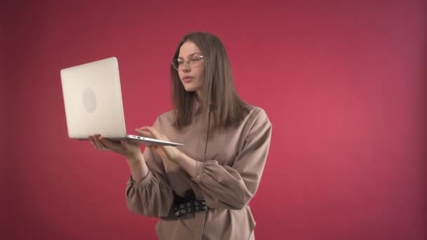 The girl looks with a surprised face at the laptop and at the camera. — Stock Video