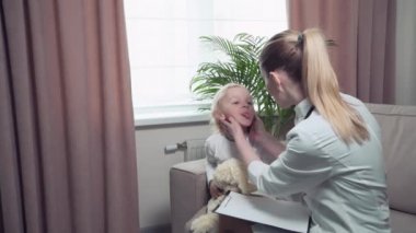 Bebek üşüttü. Doktor önlüklü bir kadın çocuğun boğazını muayene ediyor.