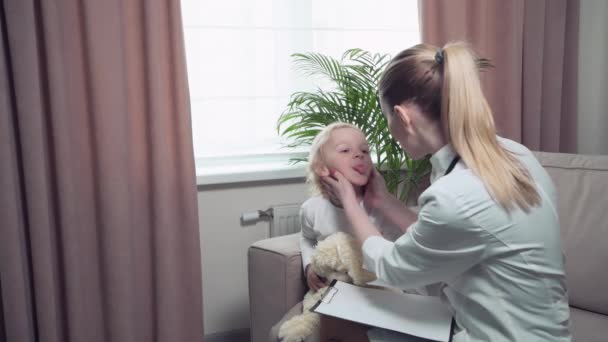 O bebé ficou constipado. Uma médica de casaco médico examina a garganta de uma criança — Vídeo de Stock